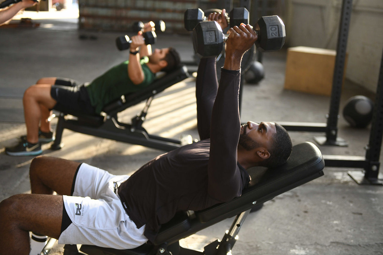 Two men lifting dumbbells in the gym