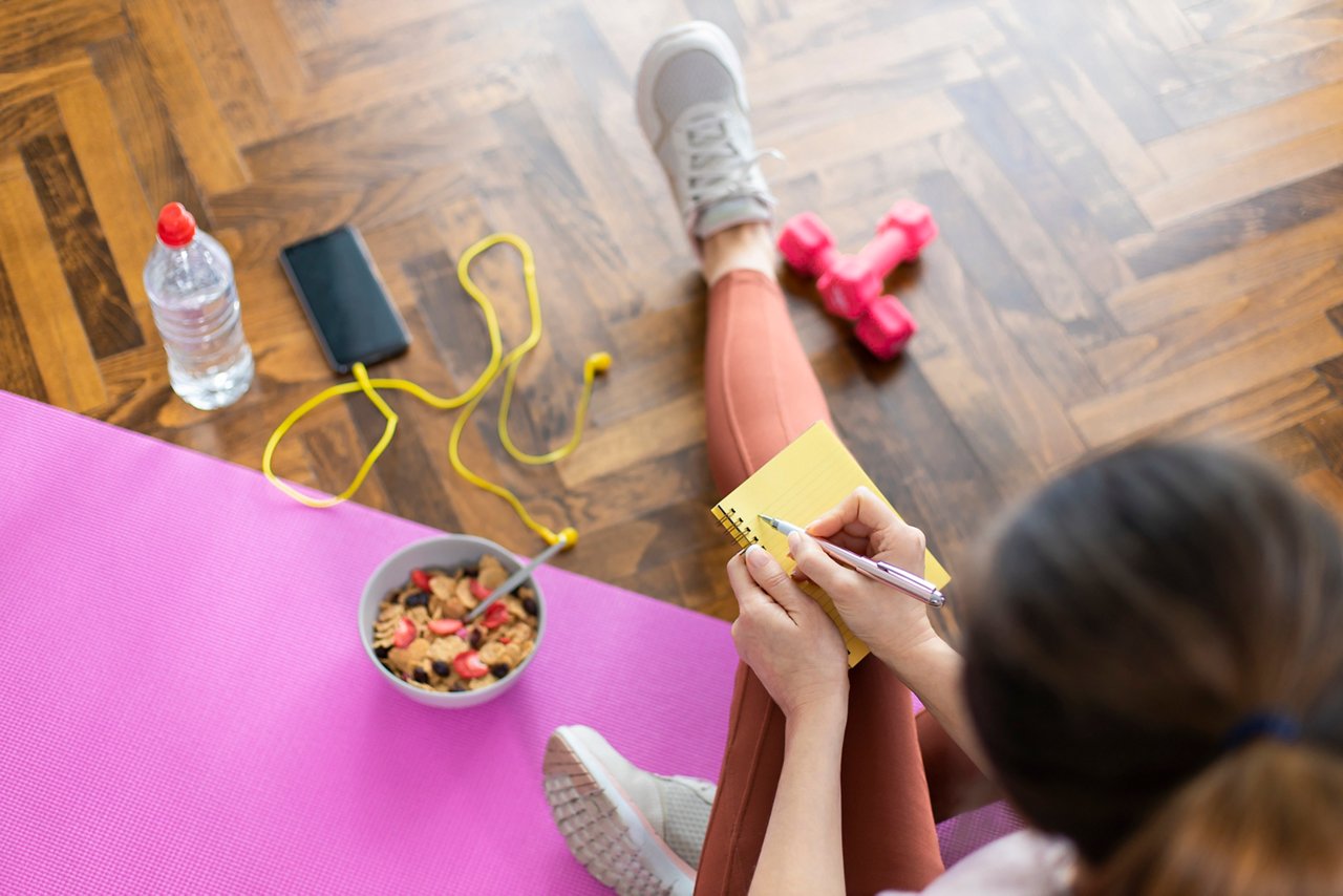 A sporty woman writing in her fitness journal to work on her New Year's resolutions